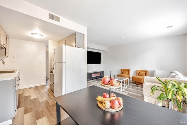 living area featuring baseboards, visible vents, and light wood-style floors