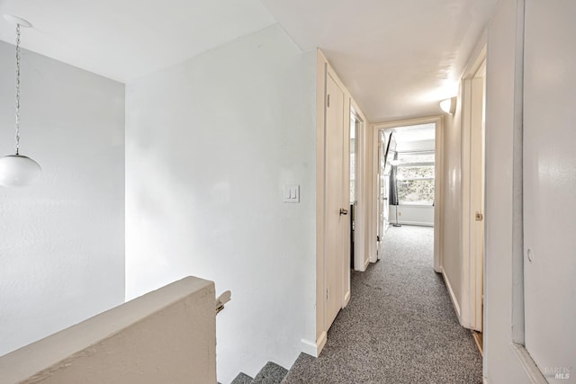 hall with an upstairs landing, baseboards, and carpet floors