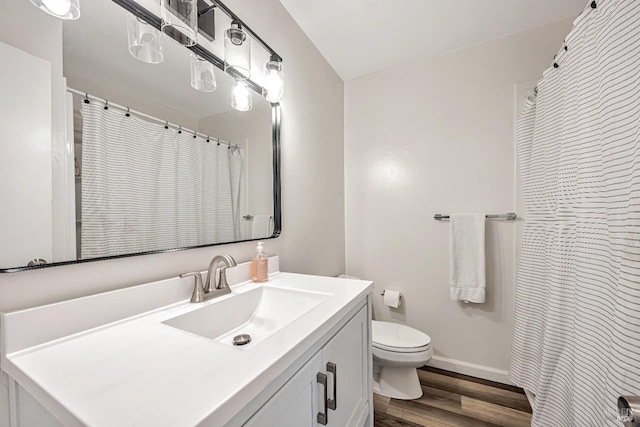 bathroom with a shower with shower curtain, baseboards, toilet, wood finished floors, and vanity