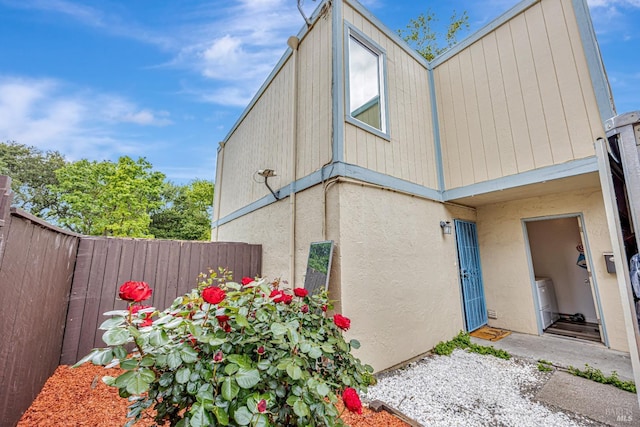 view of side of home with fence and stucco siding