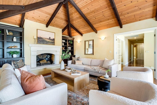 living room featuring wood ceiling, visible vents, a fireplace with raised hearth, vaulted ceiling with beams, and built in shelves