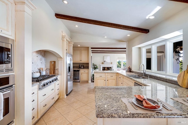 kitchen featuring a sink, stainless steel appliances, light brown cabinets, vaulted ceiling with beams, and light stone counters