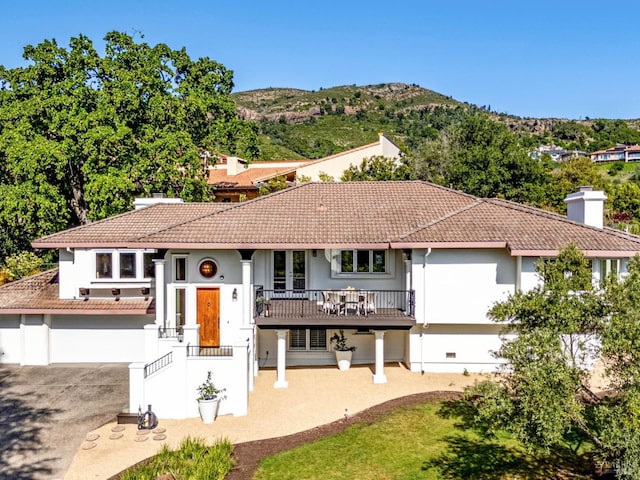 view of front facade featuring a chimney, stucco siding, driveway, and a tiled roof