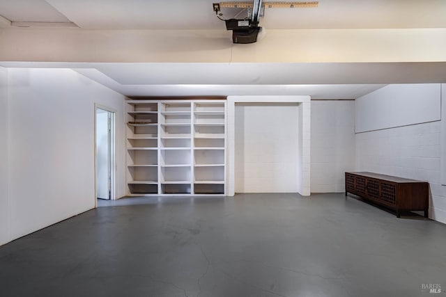 garage with a garage door opener and concrete block wall