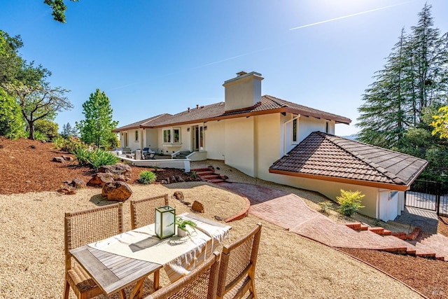 rear view of property featuring a patio area, stucco siding, and a chimney