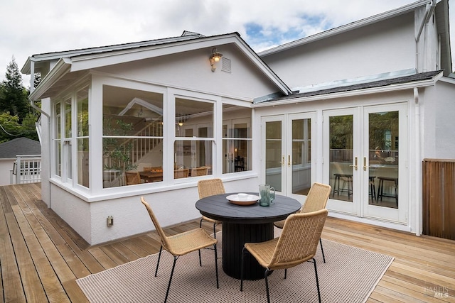 back of property with a sunroom, a deck, and french doors