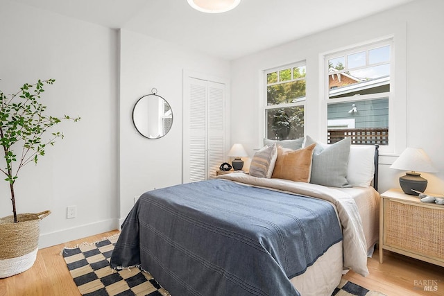 bedroom featuring baseboards, light wood-type flooring, and a closet