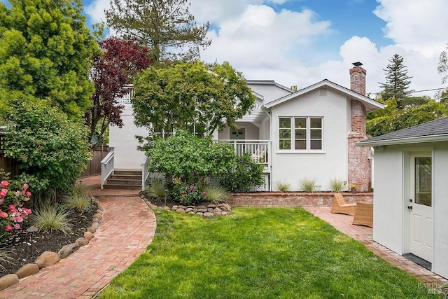 exterior space with a chimney, stucco siding, and a lawn