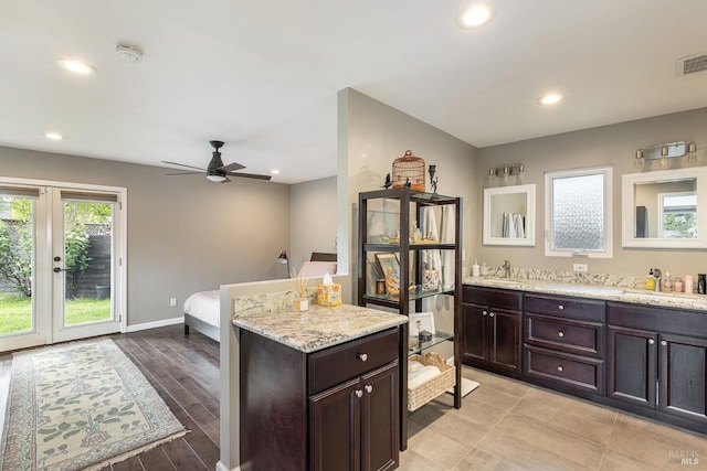 kitchen with dark brown cabinets, ceiling fan, light stone counters, a sink, and recessed lighting