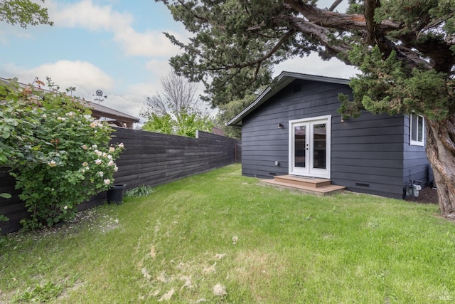 view of yard featuring fence and french doors