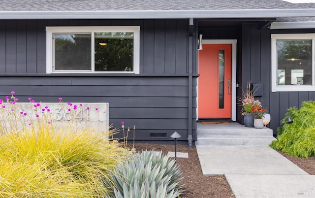entrance to property featuring board and batten siding, roof with shingles, and crawl space