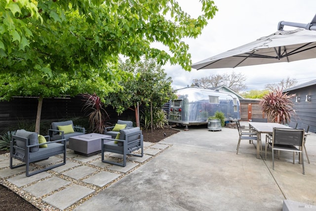 view of patio / terrace featuring an outdoor living space, a fenced backyard, an outdoor structure, and outdoor dining space
