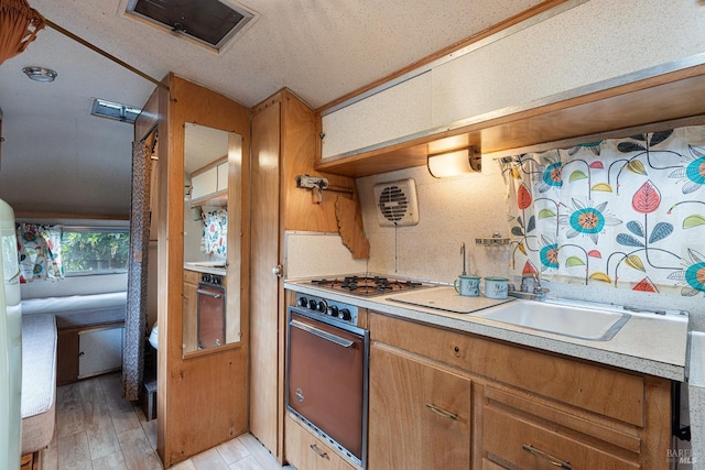 kitchen featuring lofted ceiling, wall oven, light wood-type flooring, light countertops, and brown cabinets