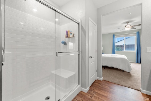 ensuite bathroom with baseboards, ensuite bathroom, a stall shower, and wood finished floors