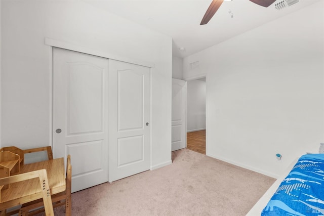 carpeted bedroom with visible vents, baseboards, ceiling fan, and a closet