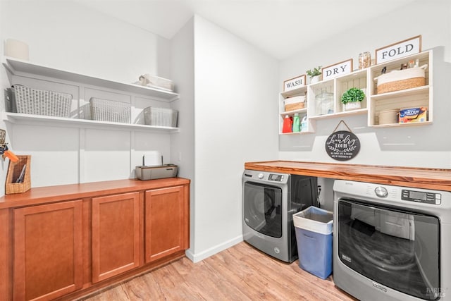 washroom featuring baseboards, laundry area, washing machine and dryer, and light wood-style flooring