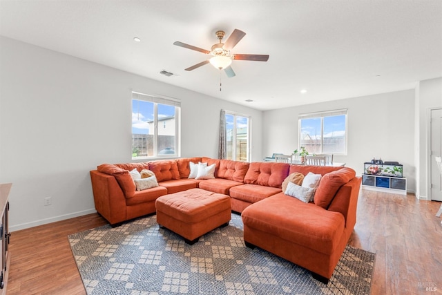 living room featuring a ceiling fan, visible vents, a wealth of natural light, and wood finished floors