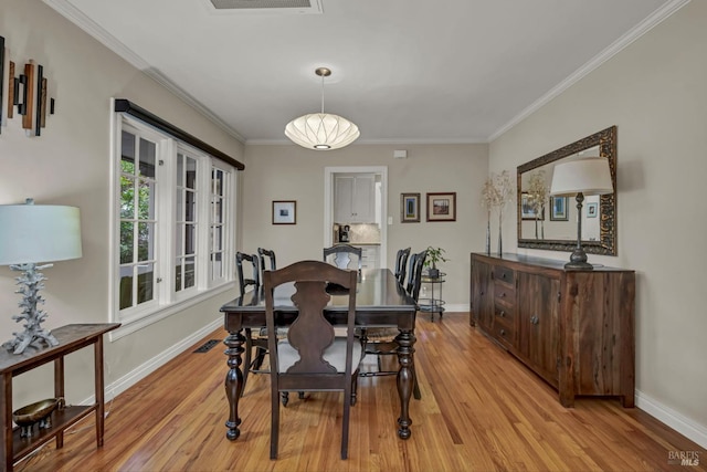 dining area featuring light wood-type flooring, ornamental molding, and baseboards