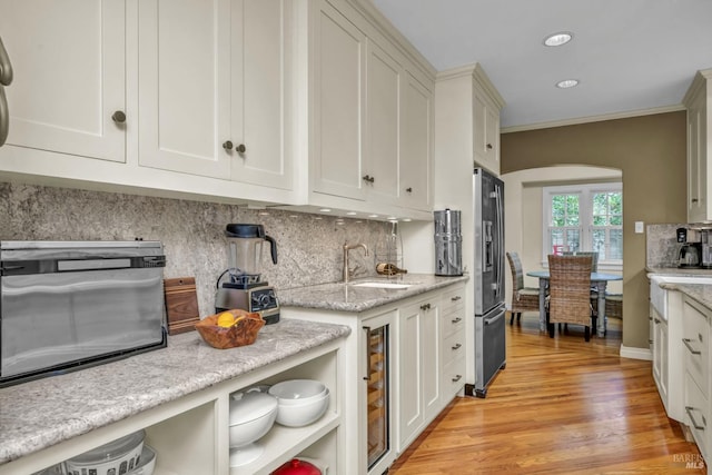 kitchen with stainless steel fridge with ice dispenser, white cabinets, backsplash, light wood-type flooring, and wine cooler