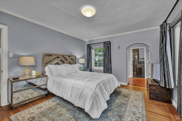 bedroom with wood finished floors, baseboards, ornamental molding, and arched walkways