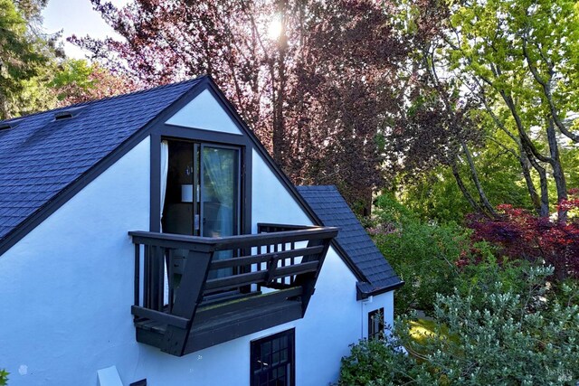 exterior space with stucco siding and a shingled roof