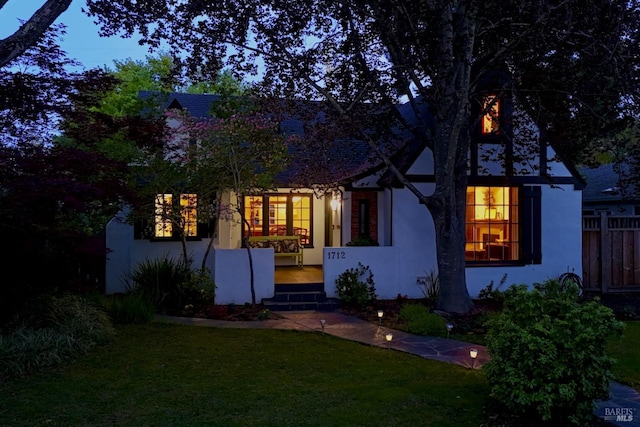 english style home with a front yard and stucco siding