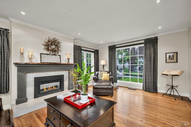 living area with wood finished floors, visible vents, crown molding, and a tile fireplace