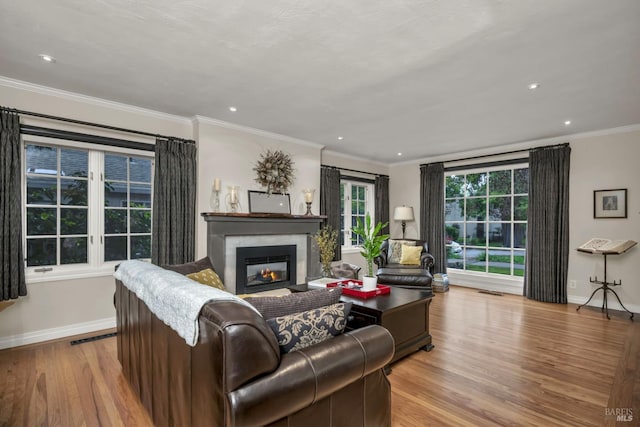 living room with recessed lighting, wood finished floors, a glass covered fireplace, baseboards, and crown molding