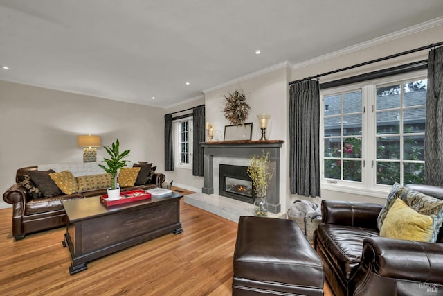 living room featuring recessed lighting, a fireplace, crown molding, and light wood finished floors