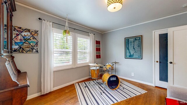 playroom with wood finished floors, ornamental molding, and baseboards