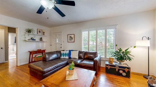 living area with a ceiling fan, baseboards, wood finished floors, and a textured ceiling