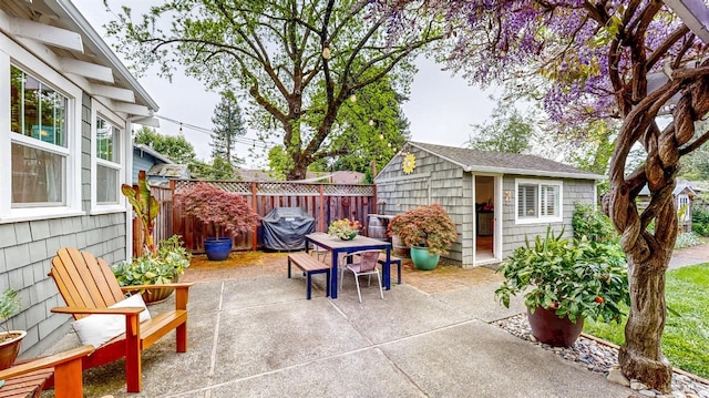 view of patio / terrace with fence, grilling area, outdoor dining area, and an outbuilding