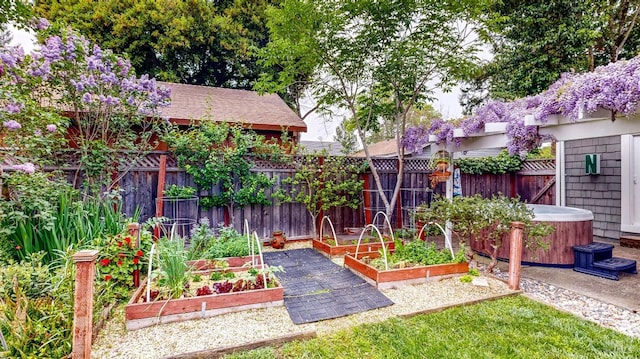view of yard featuring a vegetable garden, a fenced backyard, and a hot tub