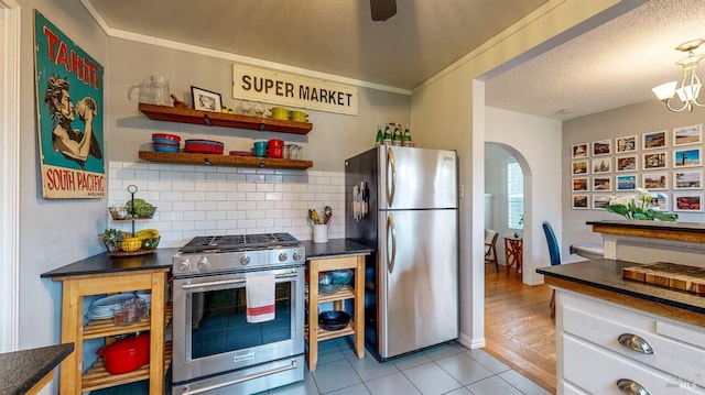 kitchen with appliances with stainless steel finishes, dark countertops, and arched walkways