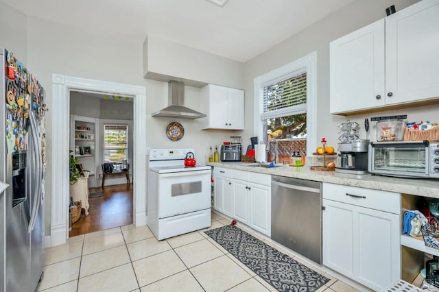 kitchen with a toaster, wall chimney range hood, white cabinets, a sink, and stainless steel appliances
