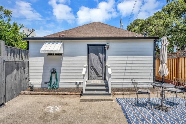 back of house with a patio, a fenced backyard, and roof with shingles