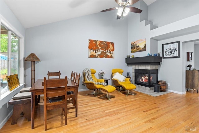 interior space with ceiling fan, a fireplace, high vaulted ceiling, baseboards, and wood finished floors