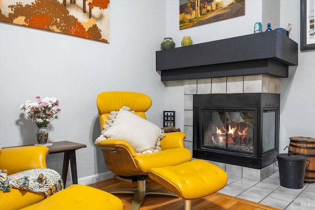 living area with baseboards and a tile fireplace
