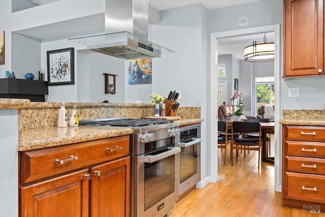 kitchen featuring light wood-style floors, light stone countertops, extractor fan, and stainless steel appliances