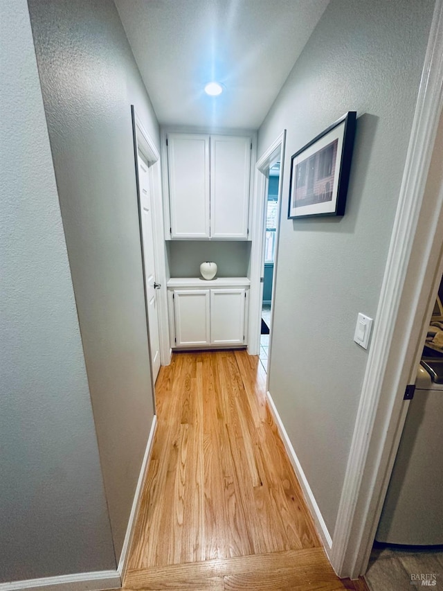 hall featuring light wood-style floors and baseboards