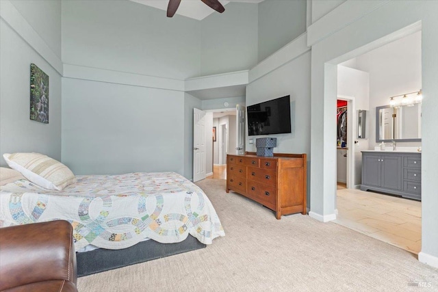 bedroom featuring baseboards, light carpet, a walk in closet, and a towering ceiling