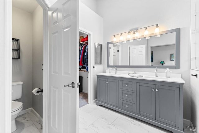 bathroom with a sink, toilet, double vanity, and marble finish floor