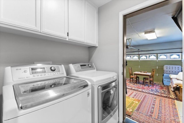 clothes washing area featuring cabinet space and washer and clothes dryer