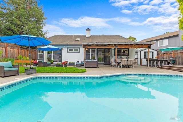 view of pool with fence, a fenced in pool, an outdoor structure, an outdoor hangout area, and a shed