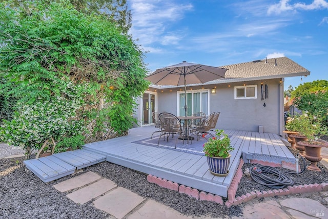 back of property featuring stucco siding, a deck, and outdoor dining area