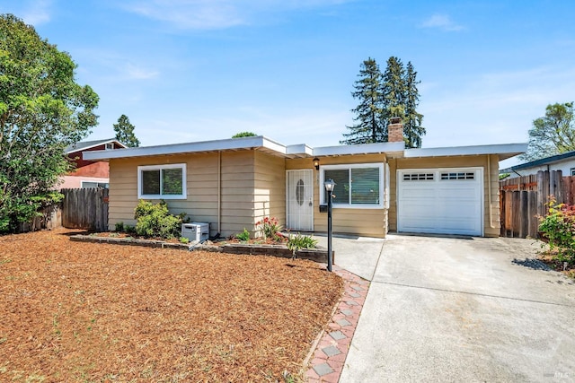 ranch-style home featuring a garage, fence, a chimney, and driveway