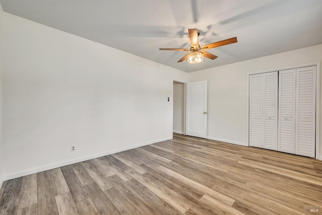 unfurnished bedroom with light wood-type flooring, a ceiling fan, baseboards, and a closet
