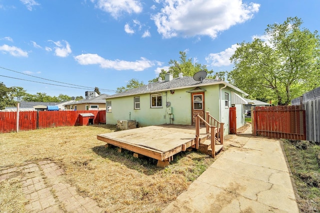 rear view of property featuring a wooden deck, stucco siding, a fenced backyard, and a chimney