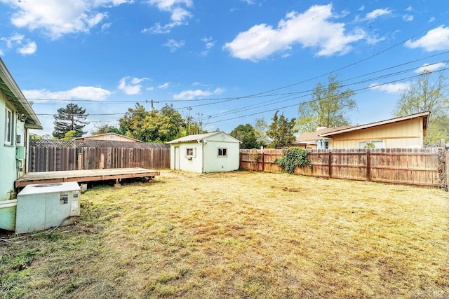 view of yard featuring a storage unit, a deck, an outdoor structure, and a fenced backyard