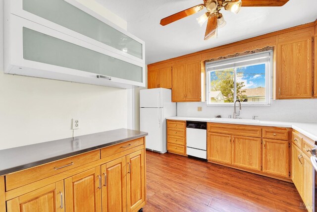 kitchen featuring a ceiling fan, wood finished floors, white appliances, and a sink
